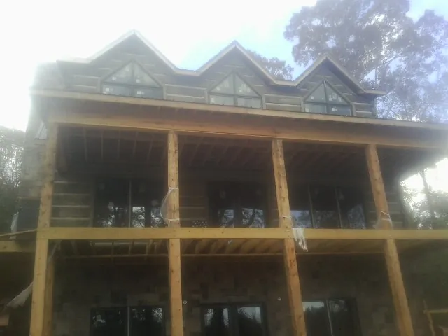 Dormers and porch framing on a large log home under construction — Roof Coating work by our crew in Sardis