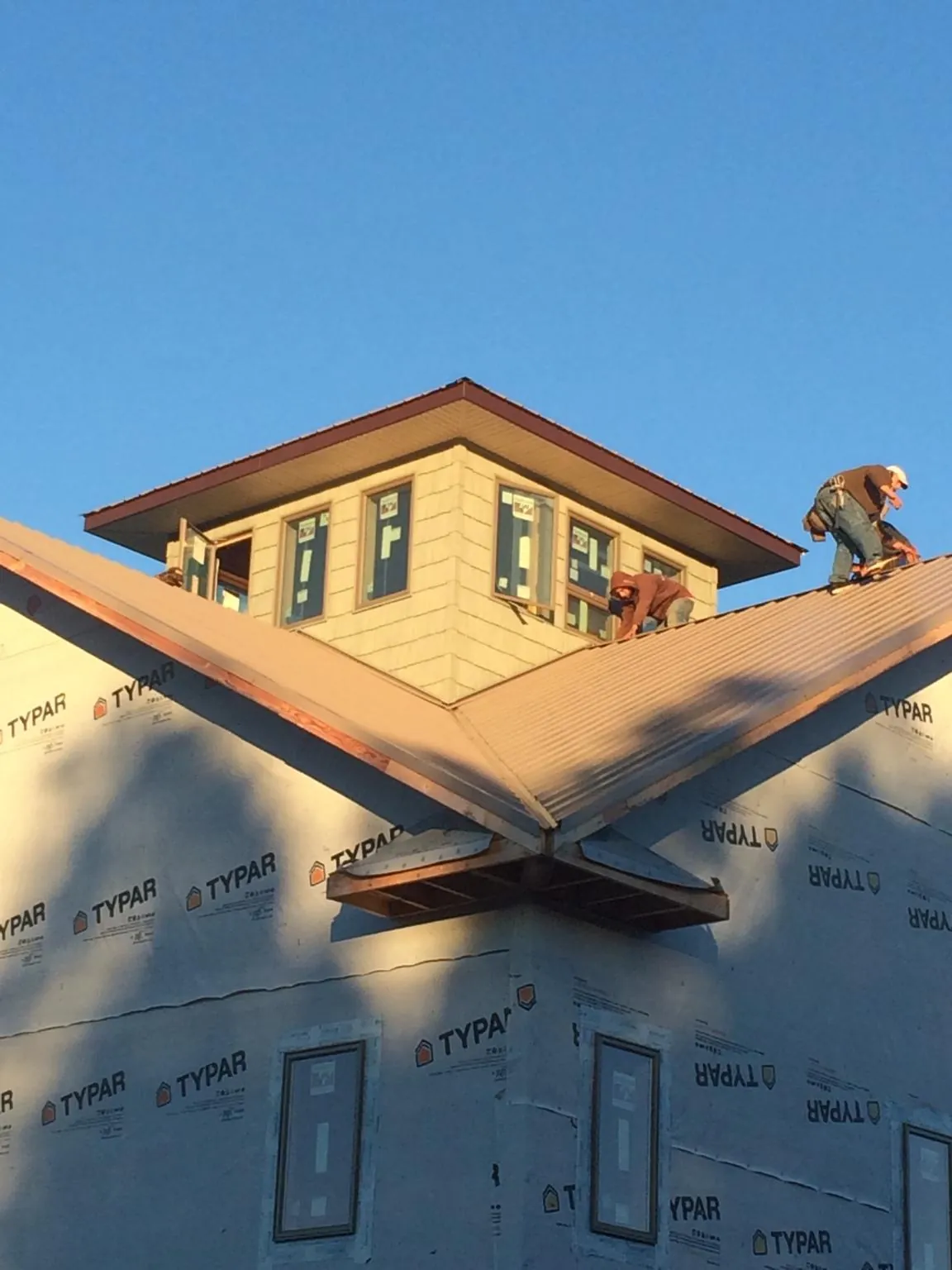 Roofers working around a rooftop cupola on a new metal roof at sunset — Roof Waterproofing in Sardis by Roofing Brothers